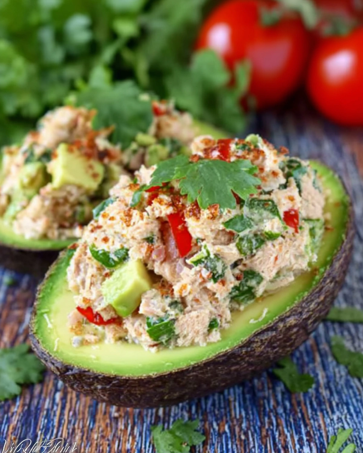 Tuna stuffed avocado halves filled with fresh tuna salad, red pepper, herbs, and seasoning, served as a healthy low carb meal.